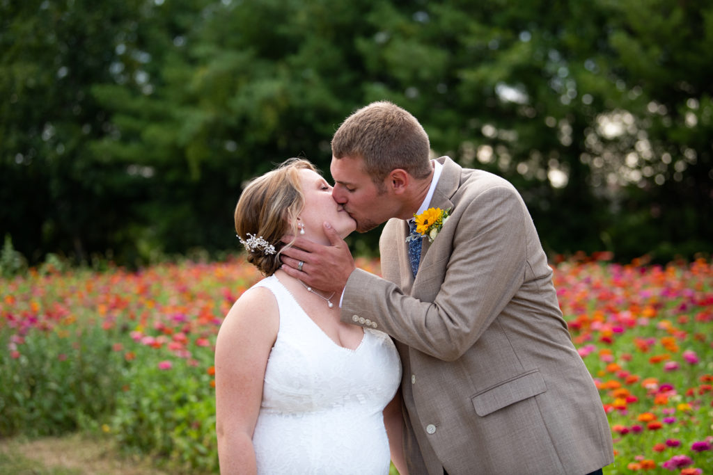 Bride and groom kissing in flower field