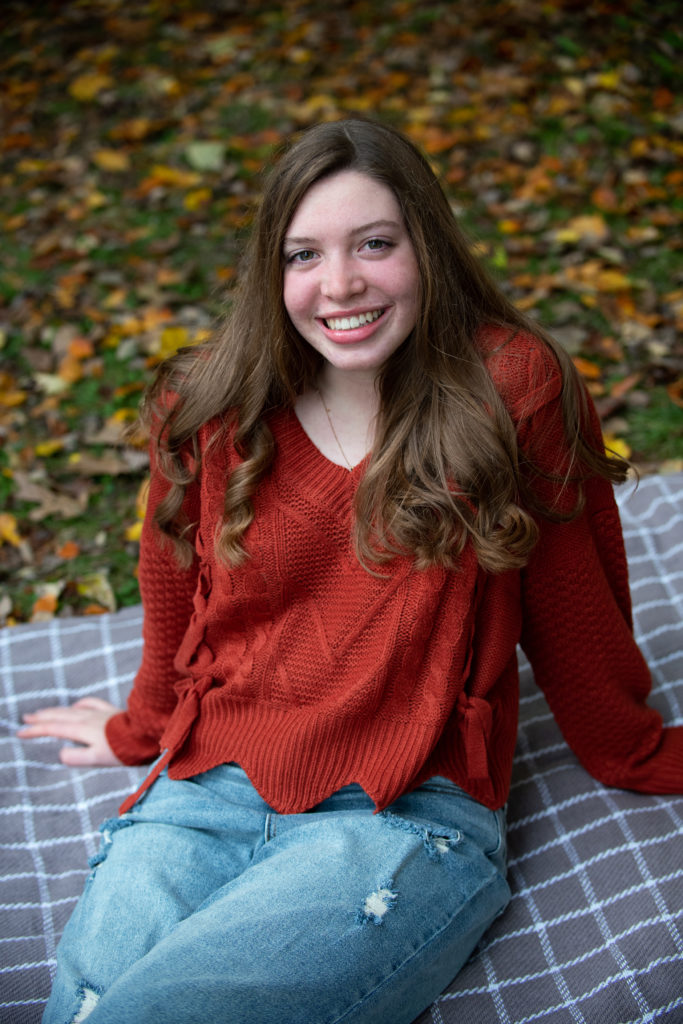 Senior portrait in fall sitting on picnic blanket